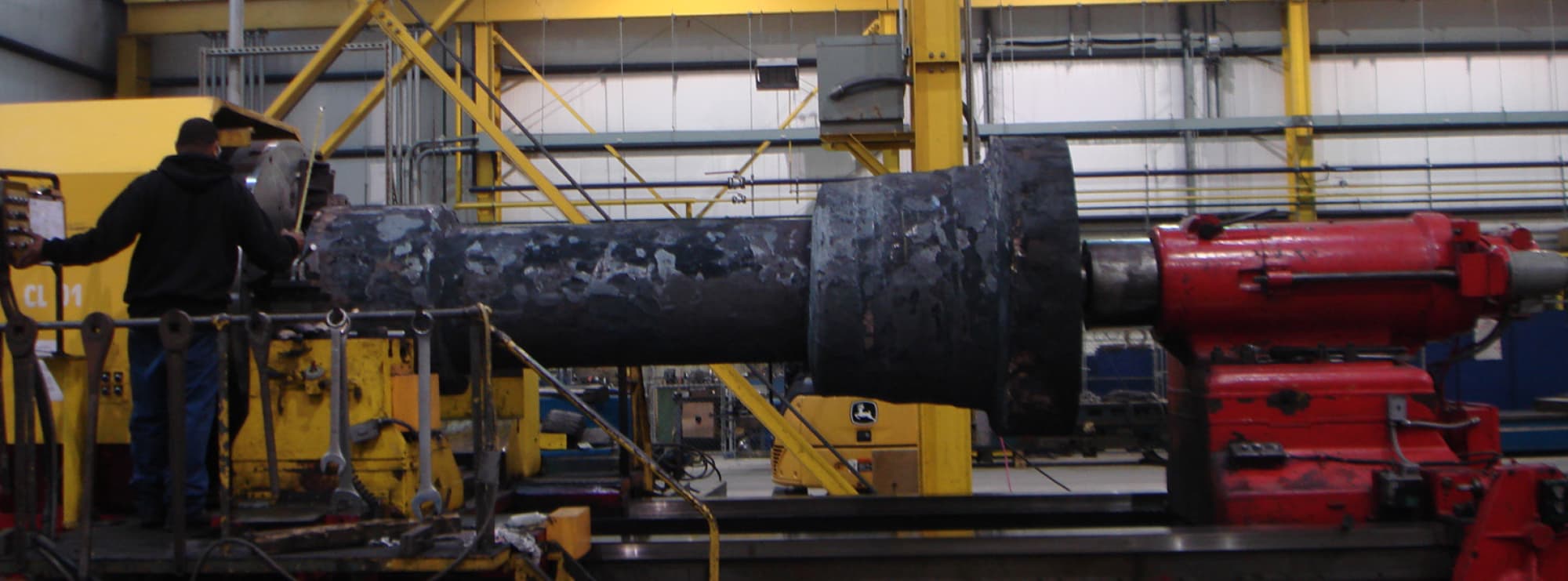 An operator beside a large forging mounted on a big lathe