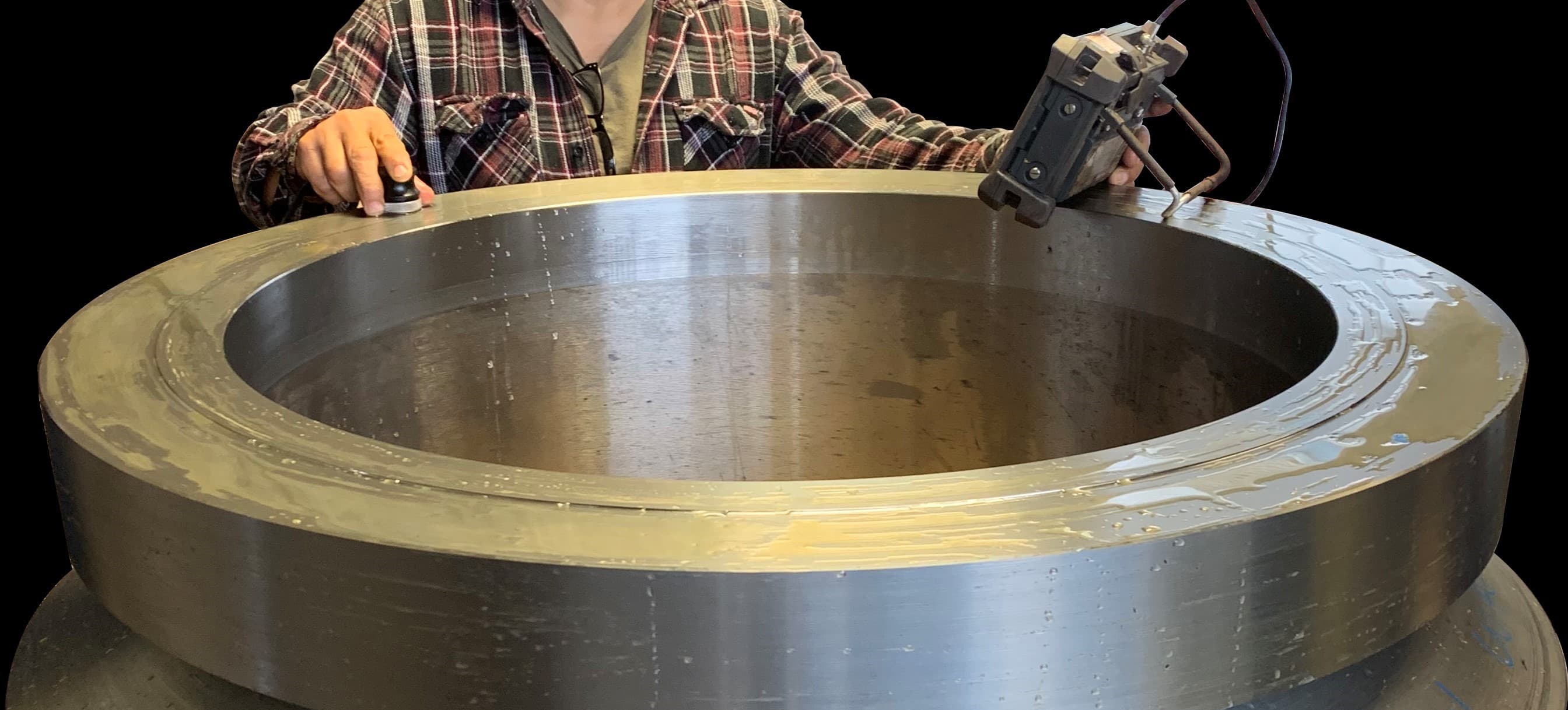 A technician performing ultrasonic testing on a large ring