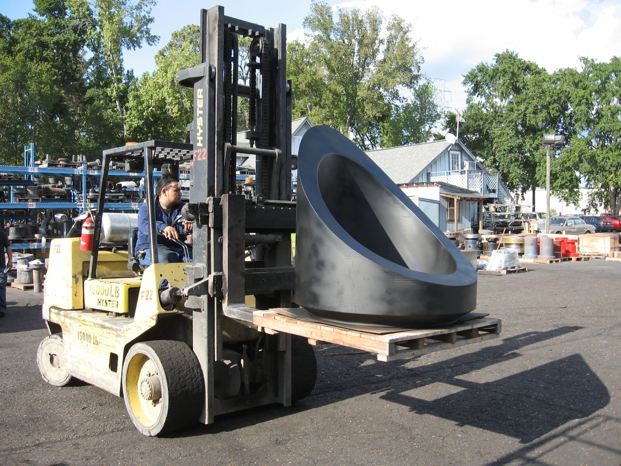 A very large blue contoured nozzle carried on a forklift