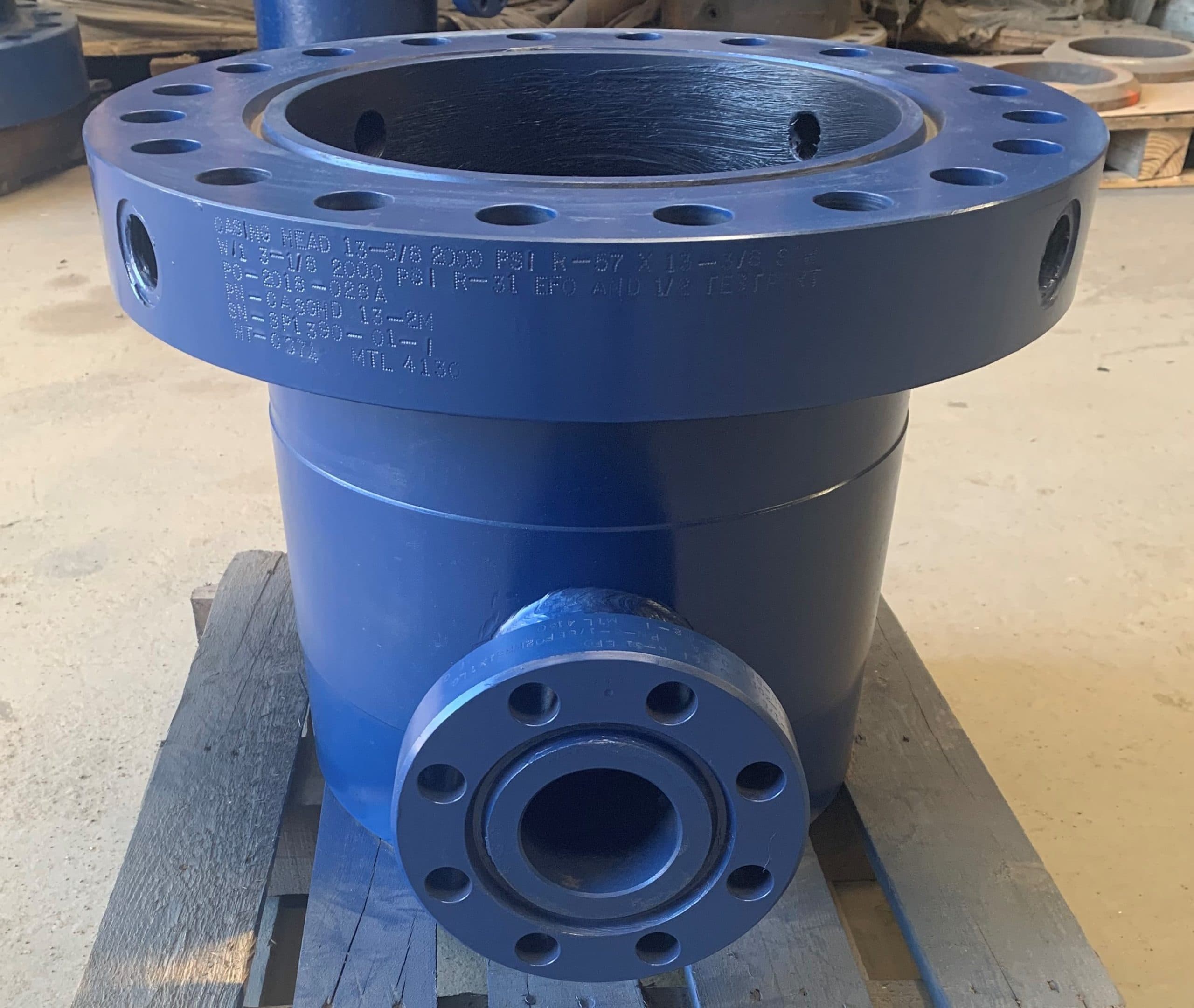 A blue casing head with side outlets on a pallet