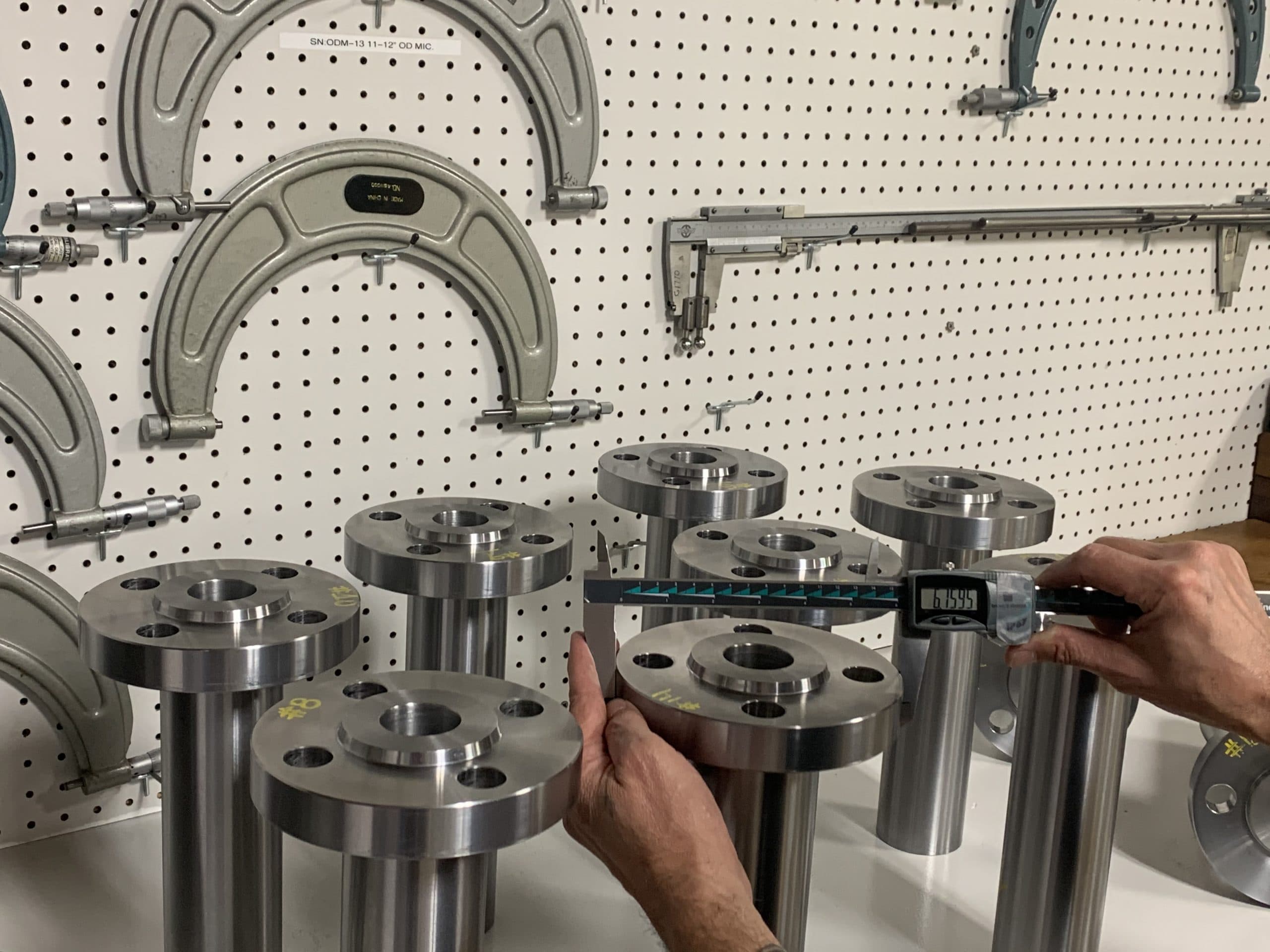 An inspector measuring machined nozzles with calipers
